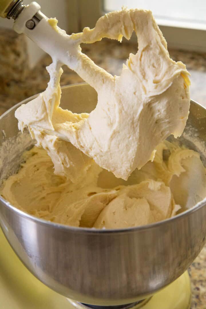 white cake batter on a paddle attachment of a stand mixer.