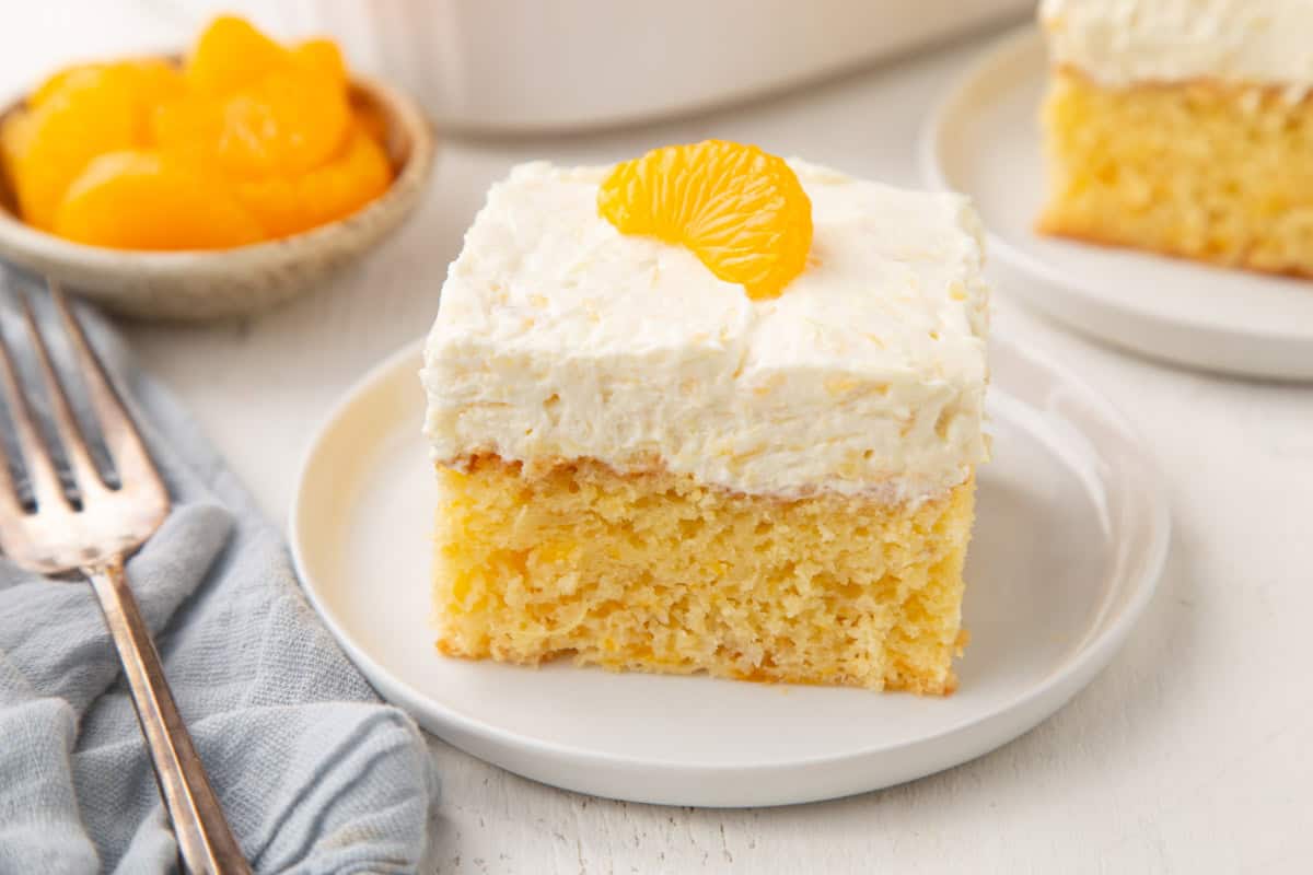 slice of mandarin orange cake topped with cool whip and a mandarin orange slice.