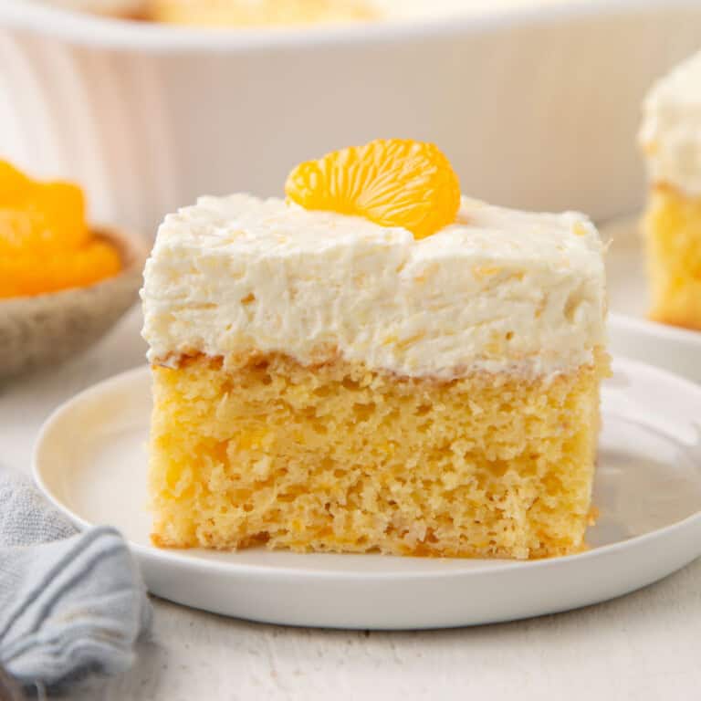 slice of mandarin orange cake topped with a fluffy frosting and a mandarin orange.
