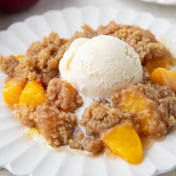 nectarine crumble with sliced nectarines and a brown sugar crumble topping, topped with a scoop of vanilla ice cream.