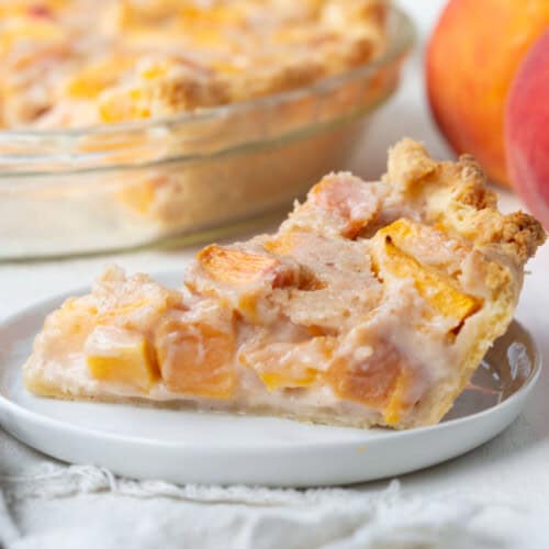slice of peach cream pie with peach pieces on a white plate.
