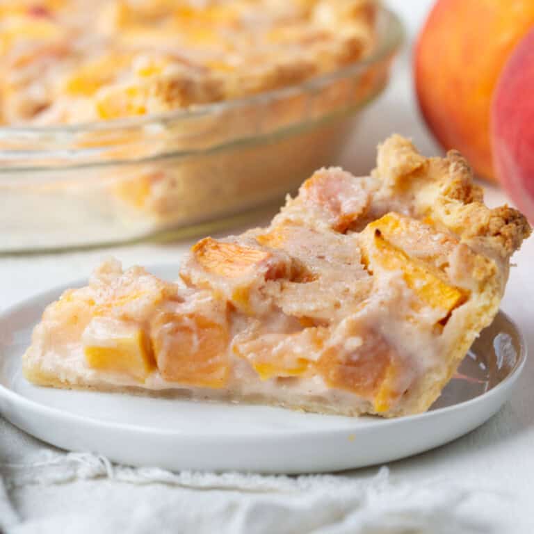 slice of peach cream pie with peach pieces on a white plate.