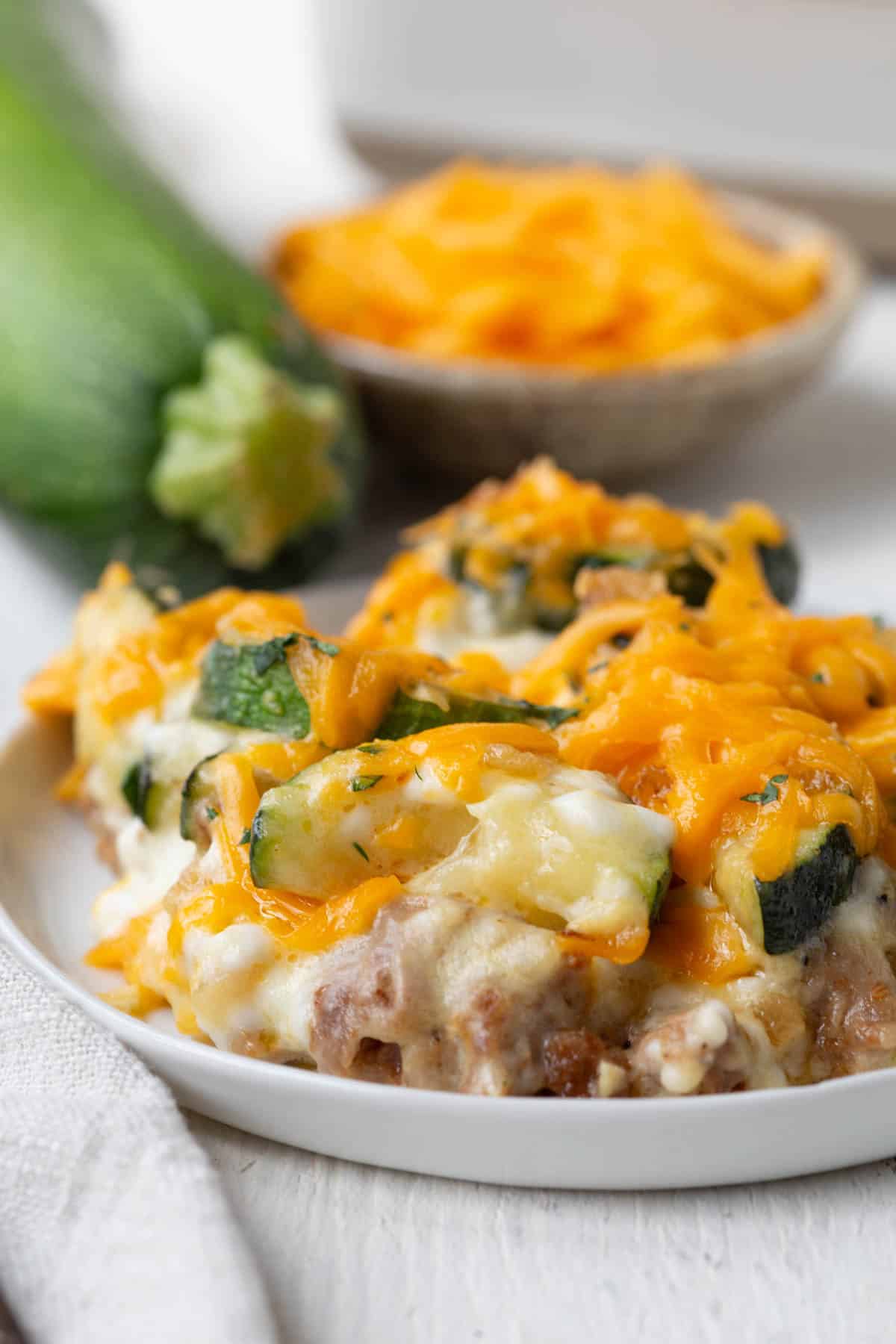 plate filled with zucchini and italian sausage casserole, topped with cheese.