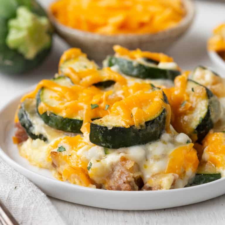 zucchini sausage casserole topped with cheese on a plate.
