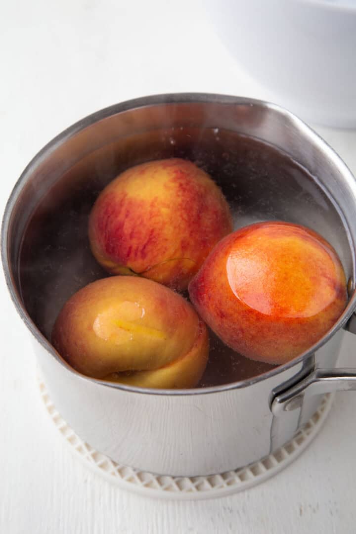 peaches in boiling water in a saucepan.