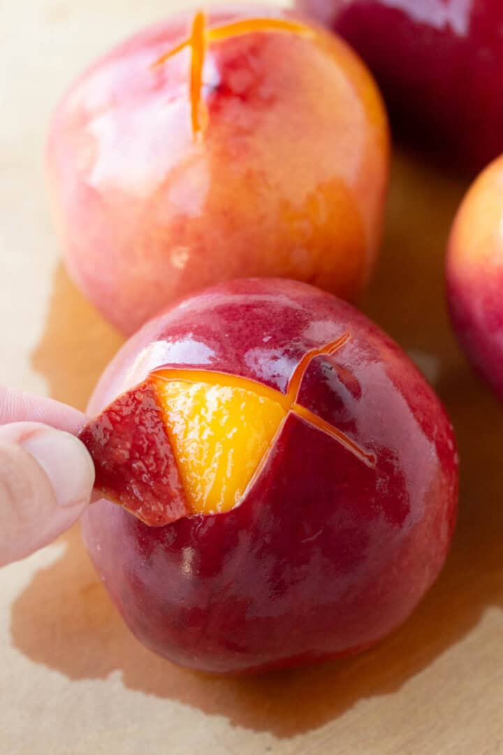 hand peeling skin away from a peach or nectarine.