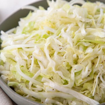 vinegar coleslaw made with shredded cabbage and onion in a green bowl.