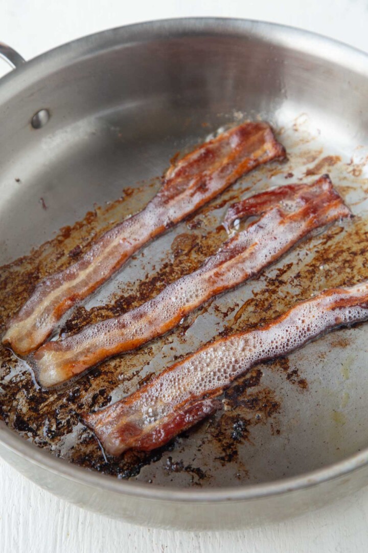three pieces of crisp bacon in a skillet.