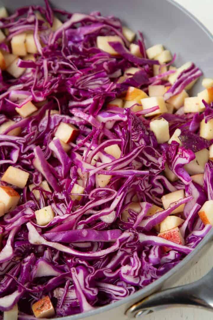 raw cabbage and apples in a sauté pan.