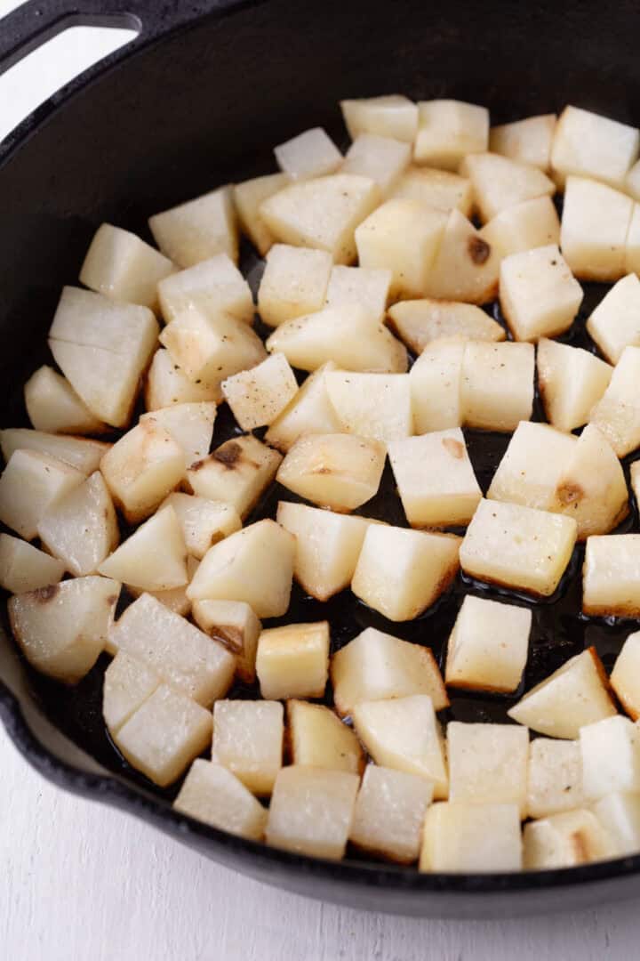 a layer of uncooked potatoes in a cast iron skillet.