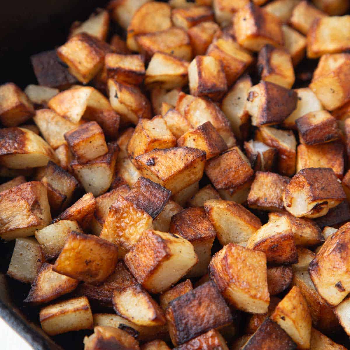 crispy home fried potatoes cut into cubes in a cast iron skillet.