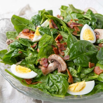 baby spinach with hard boiled eggs, mushrooms, and crispy bacon pieces in a hot bacon dressing.