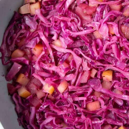 sweet and sour purple cabbage in a pan with pieces of apples.