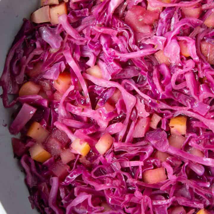 sweet and sour purple cabbage in a pan with pieces of apples.