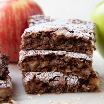 three apple oat bars with powdered sugar on top, stacked on top of each other.