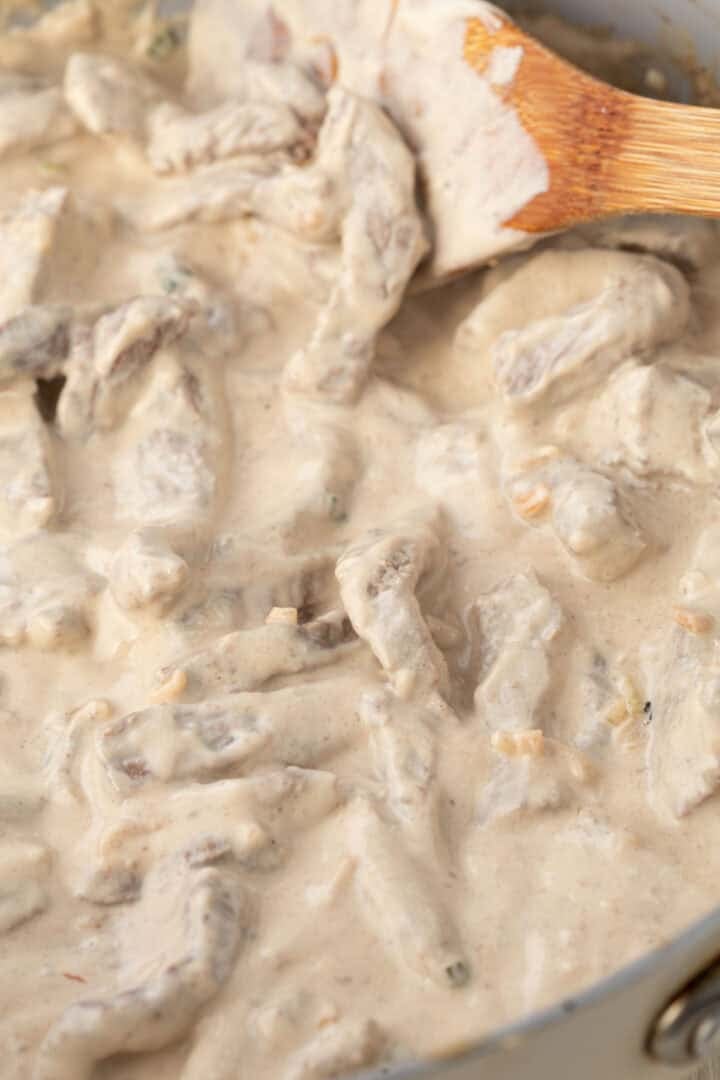 strips of beef in a creamy onion sauce in a skillet.