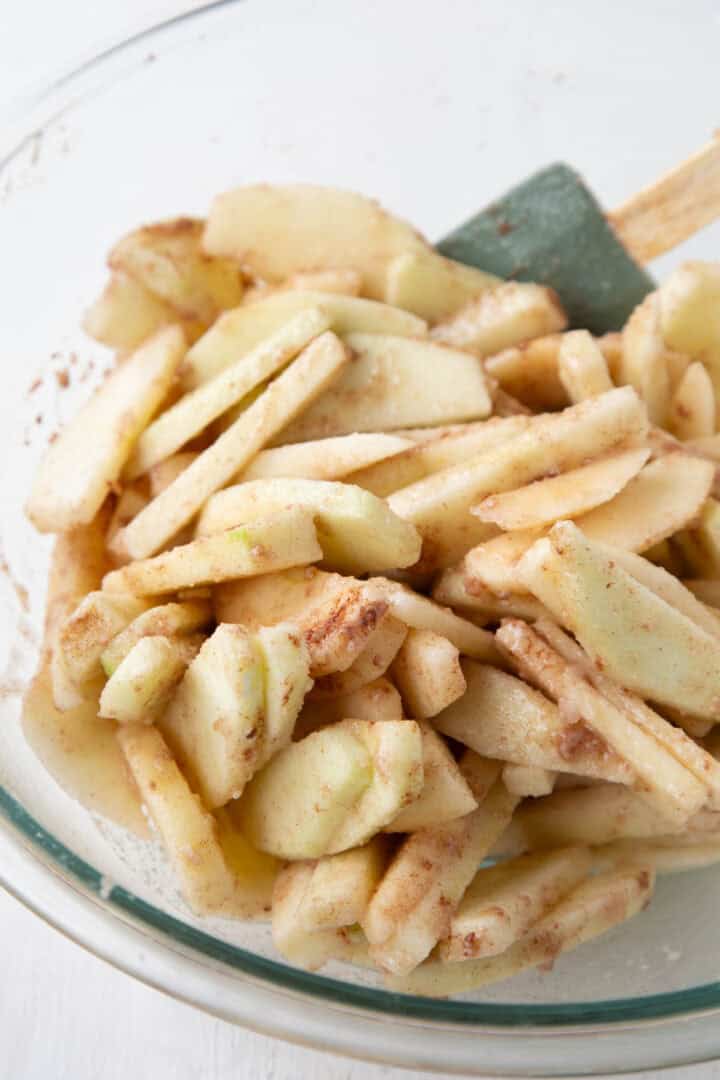 sliced apples and cinnamon in a mixing bowl.