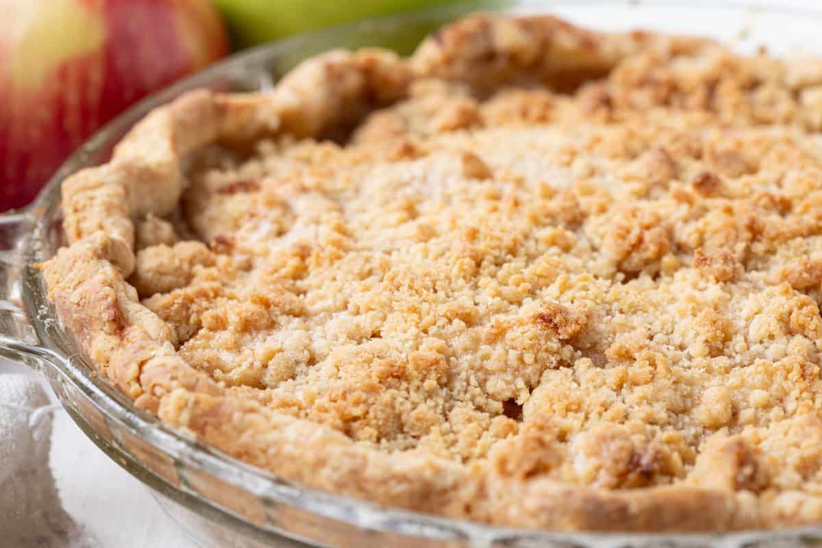 whole dutch apple pie with a flaky pastry crust and a crumble topping.