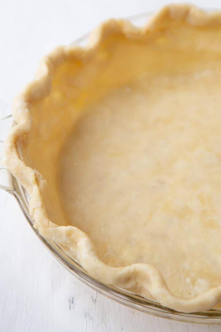 unbaked fluted pie crust in a glass pie dish.