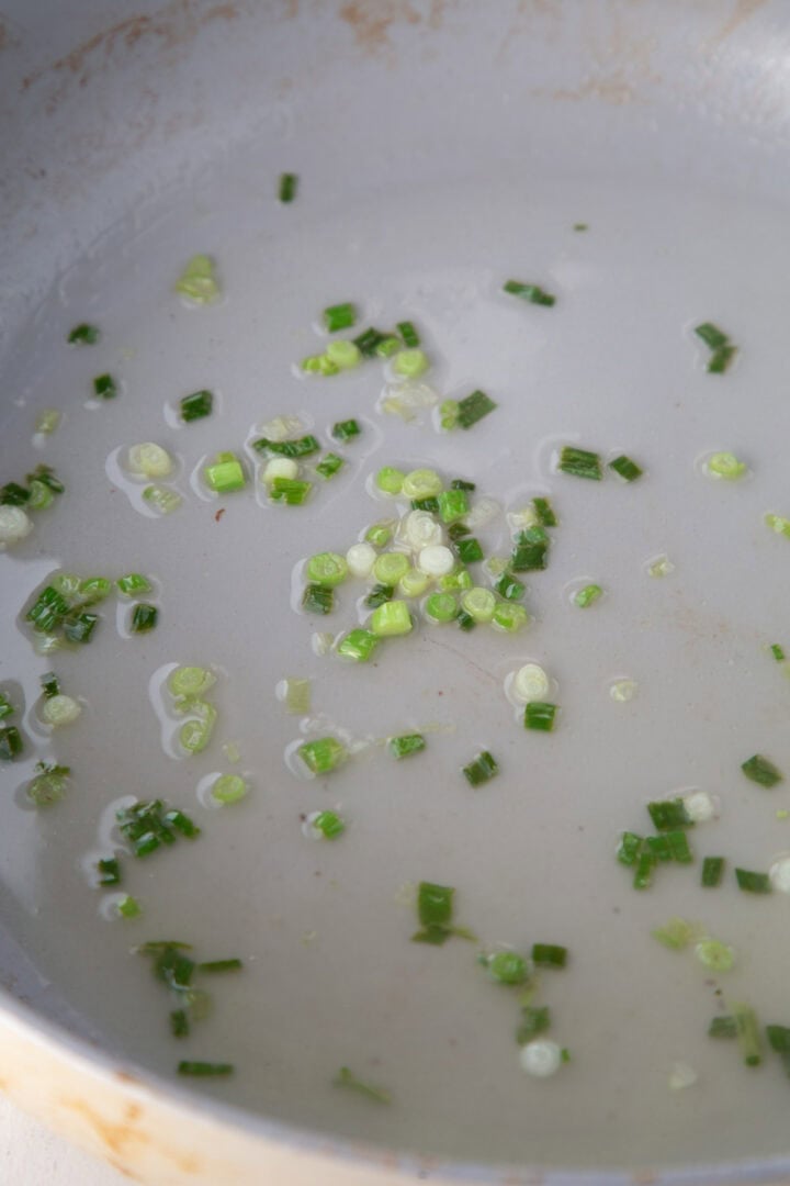 green onions cooking in a skillet.