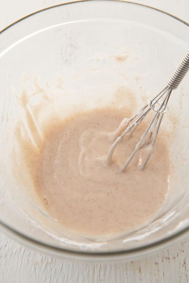 cinnamon glaze in a bowl with a whisk.