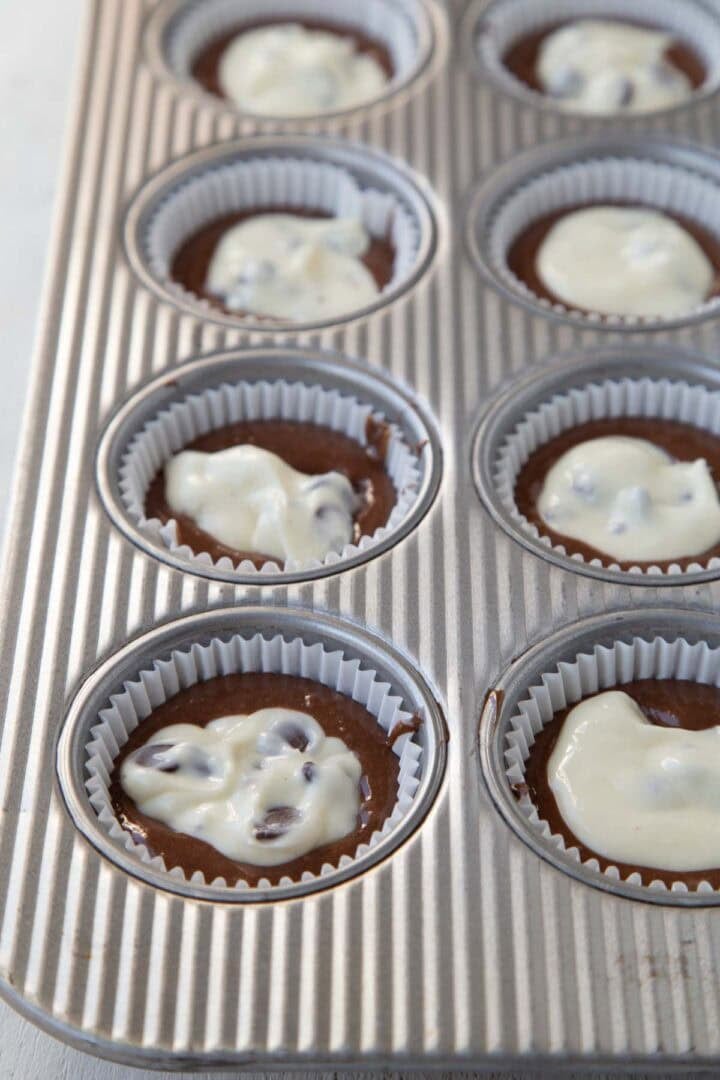chocolate cake batter in muffin cups, topped with a dollop of a chocolate chip cream cheese mixture in each cup.